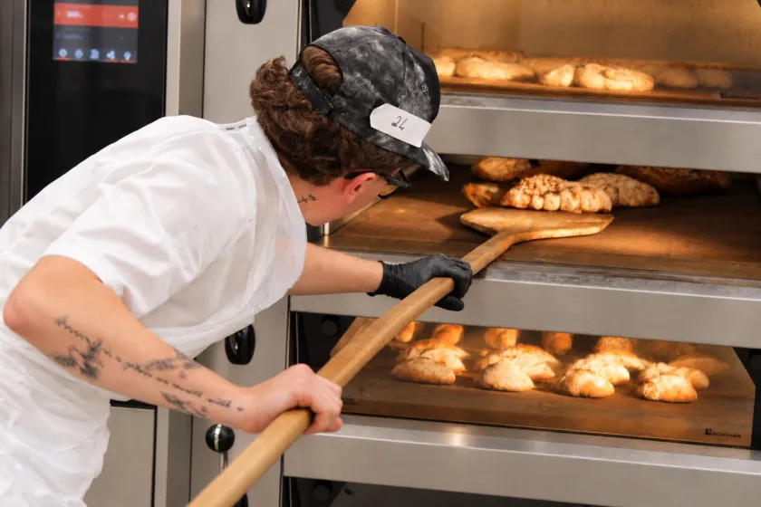 Apprenti qui met du pain au four